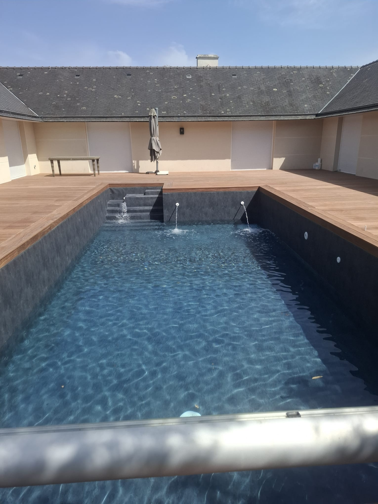 Piscine bordée d'une terrasse en Cumaru, jets d'eau et marches d'accès au bassin